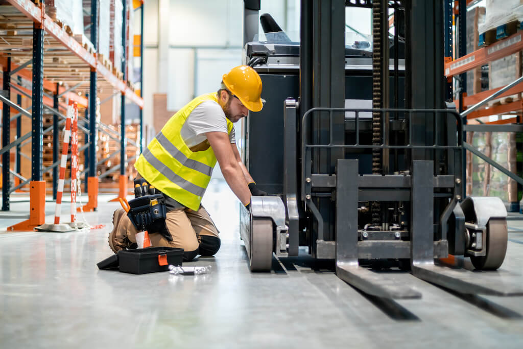 Mechanic checking a forklift in a warehouse as part of a Preventive Maintenance Program